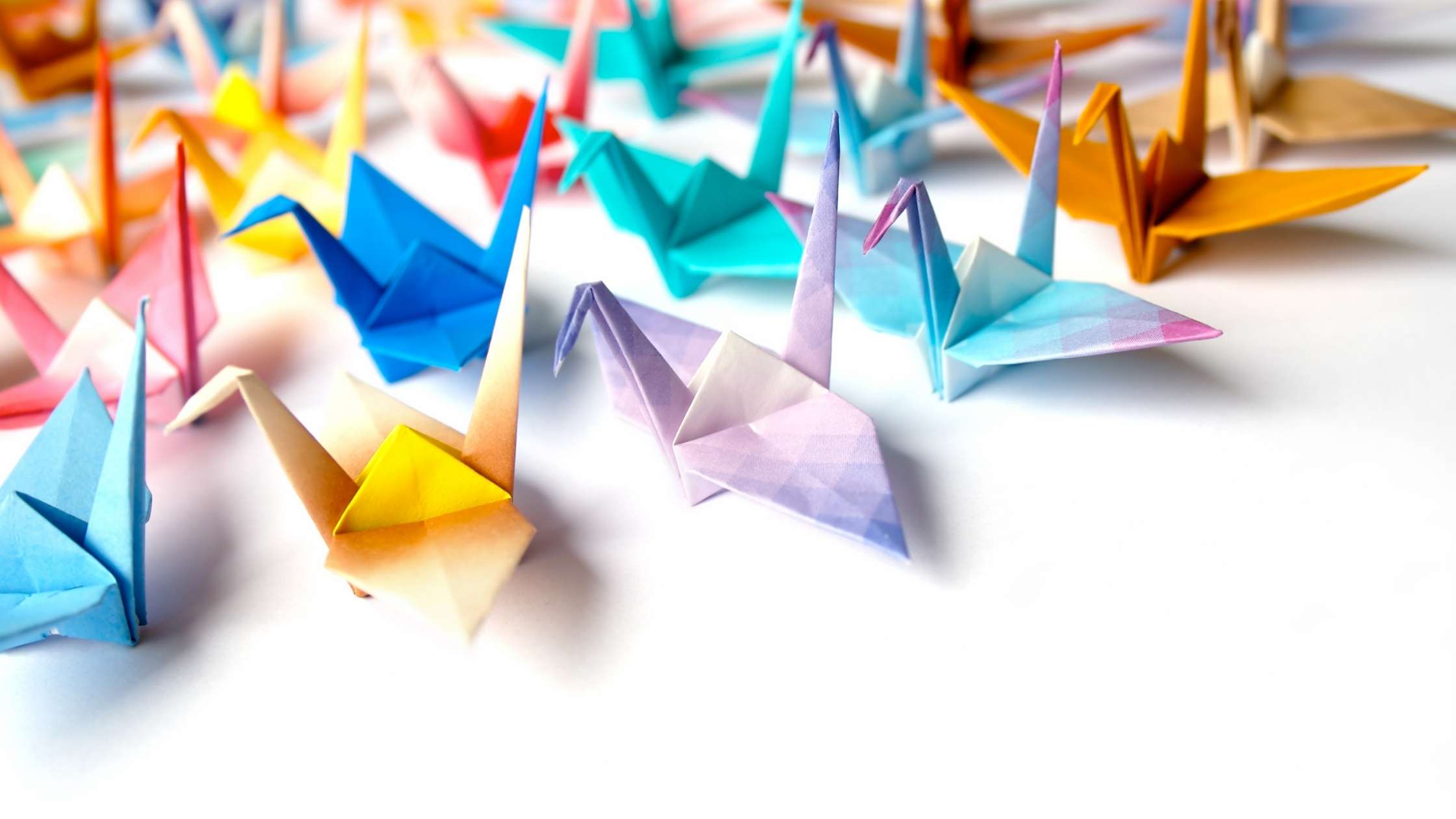 Flutter concept; collection of multicoloured origami paper cranes on a light background